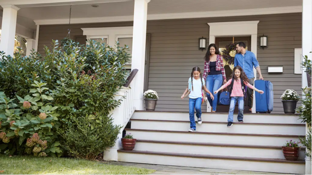 Image of a family enjoying a lock-and-leave lifestyle: walking away from their home with luggage, ready for their next adventure.