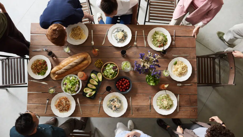 Image of a group of friends seated at a Friendsgiving feast tasting over the food.